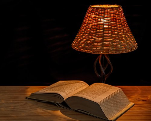 A reading lamp illuminating a desk in the evening